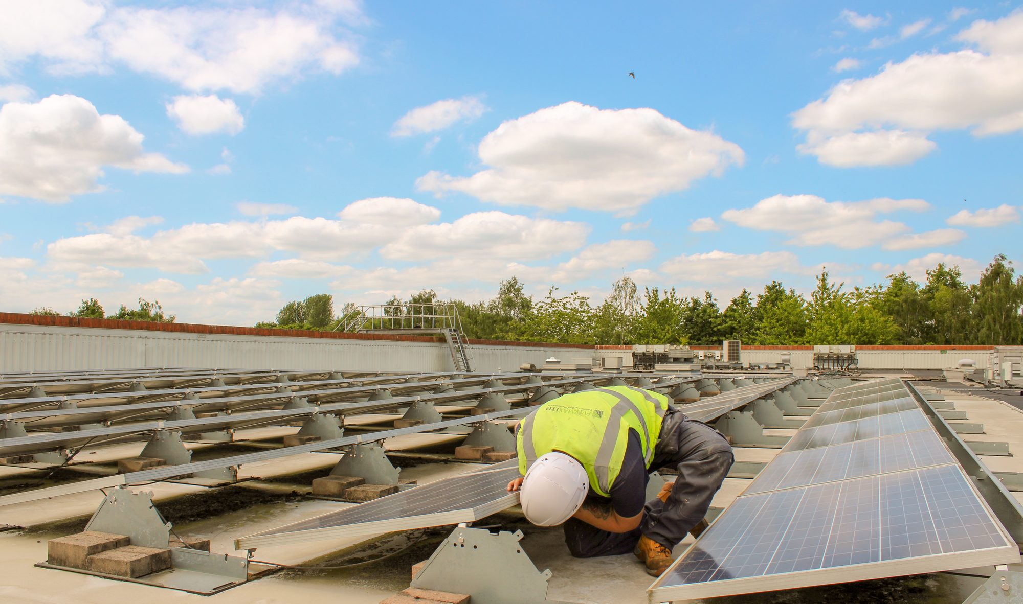 Evermax operative working on a large commercial roof with rooflights under a clear sky