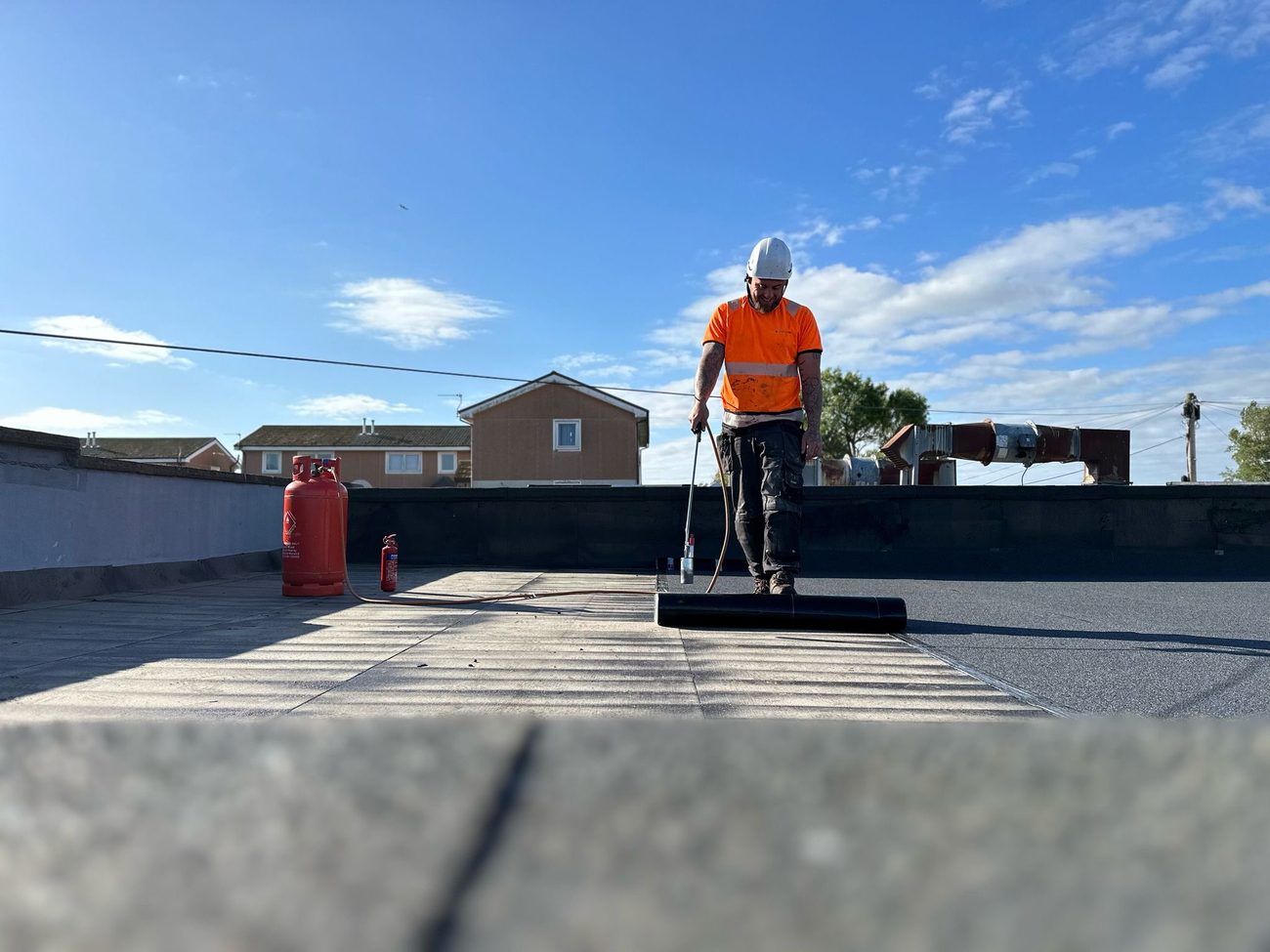 Operative applying a liquid waterproofing system to a refurbished flat commercial roof