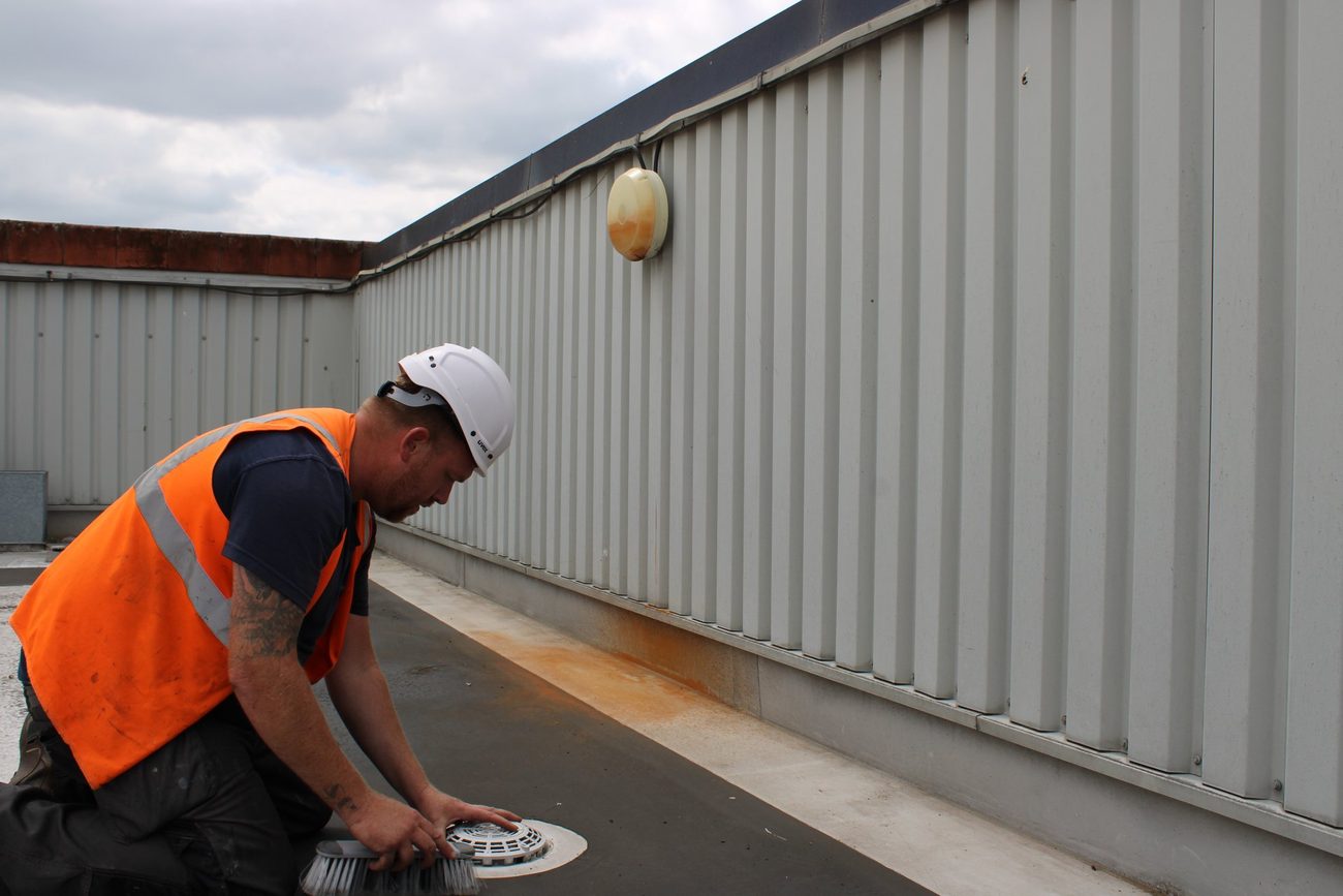 Evermax operative inspecting a detail on a flat commercial roof during a survey